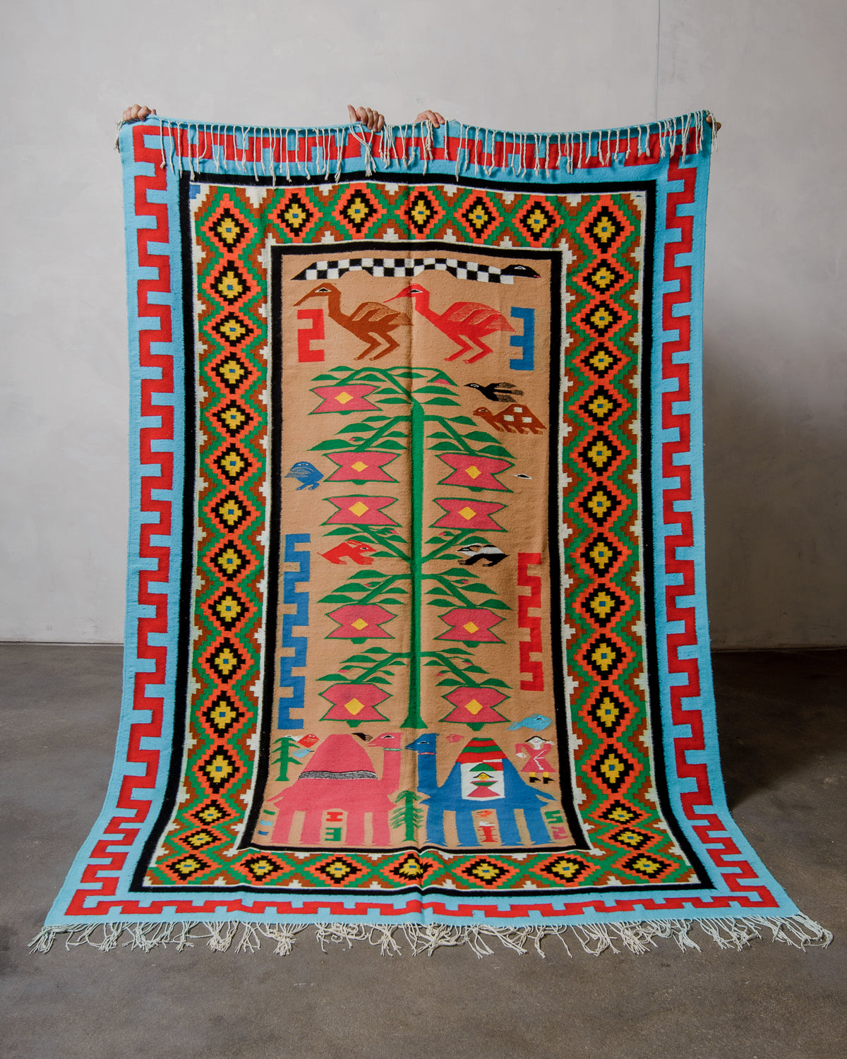 Colorful patterned rug with geometric designs and animals on a plain background